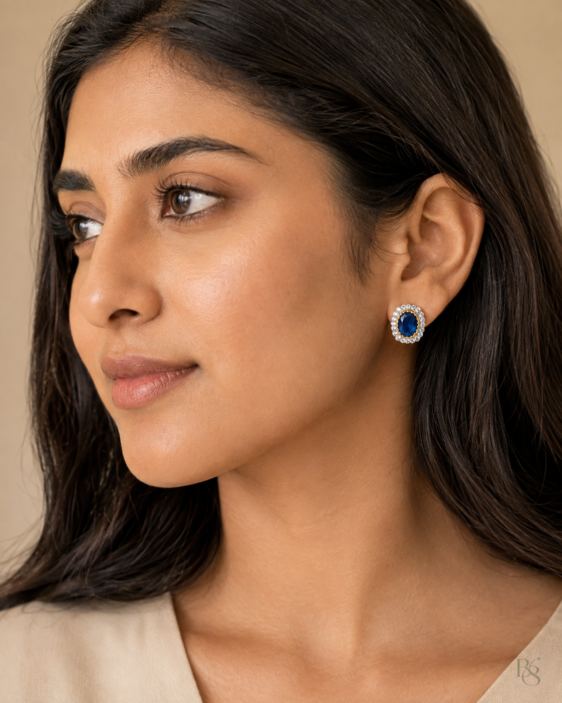 Model wearing Regal Oval Halo Stud Earrings in Sapphire Blue